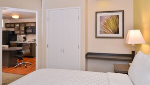A hotel room with a bed, a desk, a chair, a nightstand, a lamp, and a framed picture on the wall. - Candlewood Suites Austin-Round Rock by IHG (Round Rock)