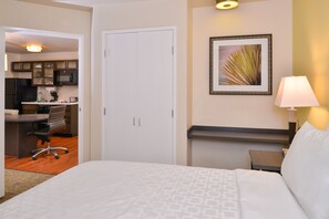 A hotel room with a bed, a desk, a chair, a nightstand, a lamp, and a framed picture on the wall. - Candlewood Suites Austin-Round Rock by IHG (Round Rock)