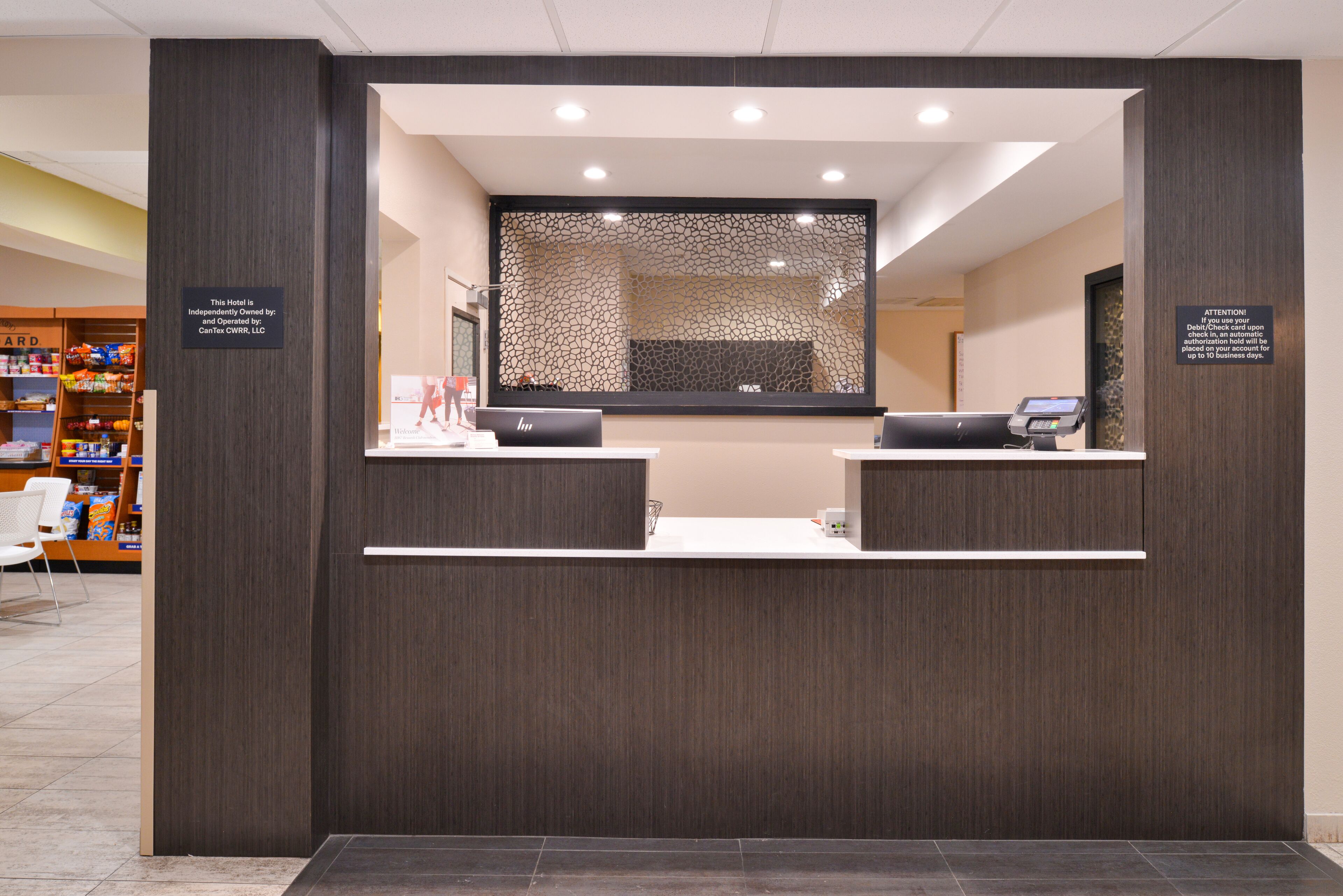 A hotel reception desk with a modern design, featuring a dark wood finish and a glass partition.