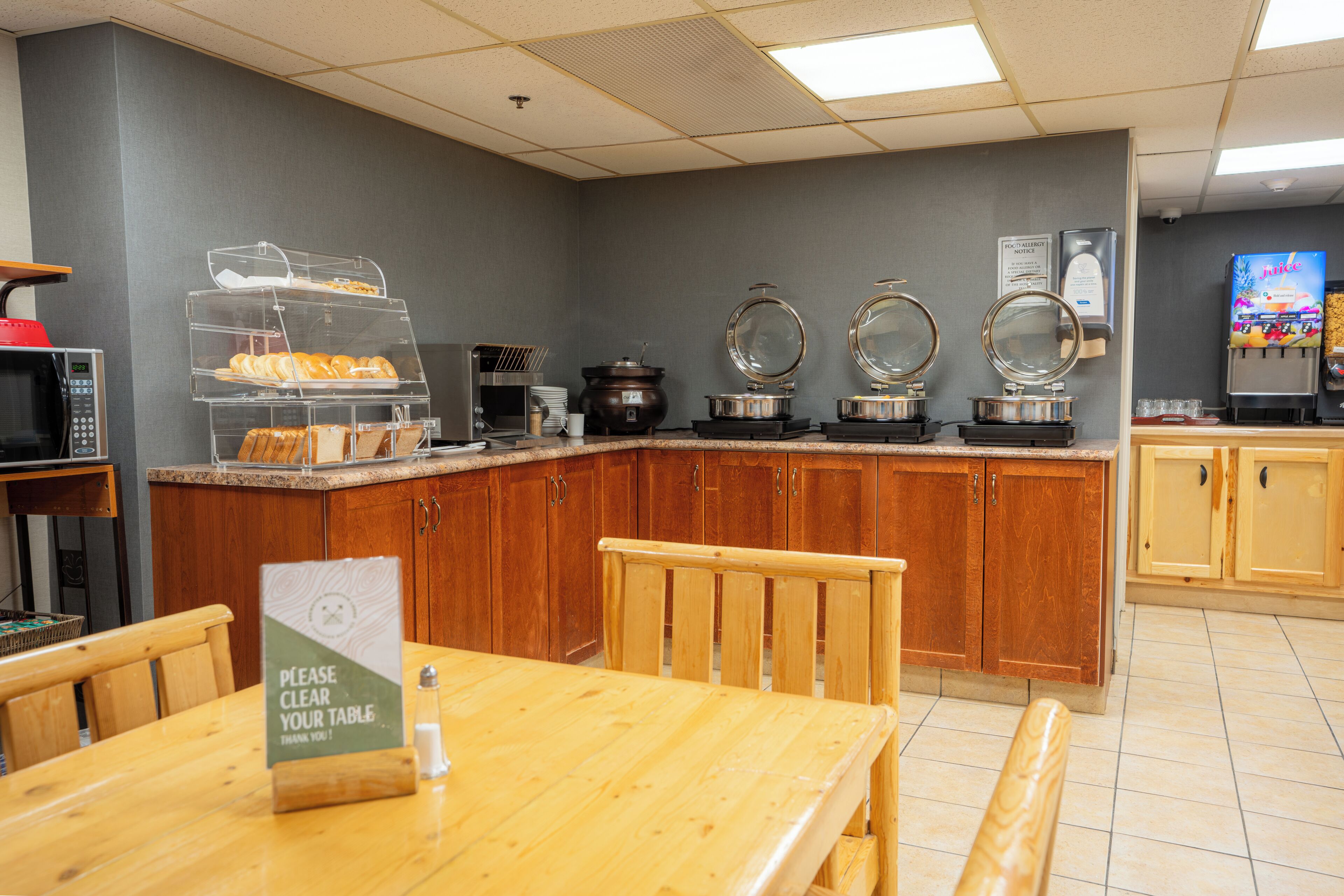 A breakfast area with a buffet counter, a microwave, and a juice dispenser.