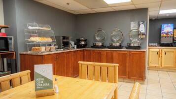 A breakfast area with a buffet counter, a microwave, and a juice dispenser.
