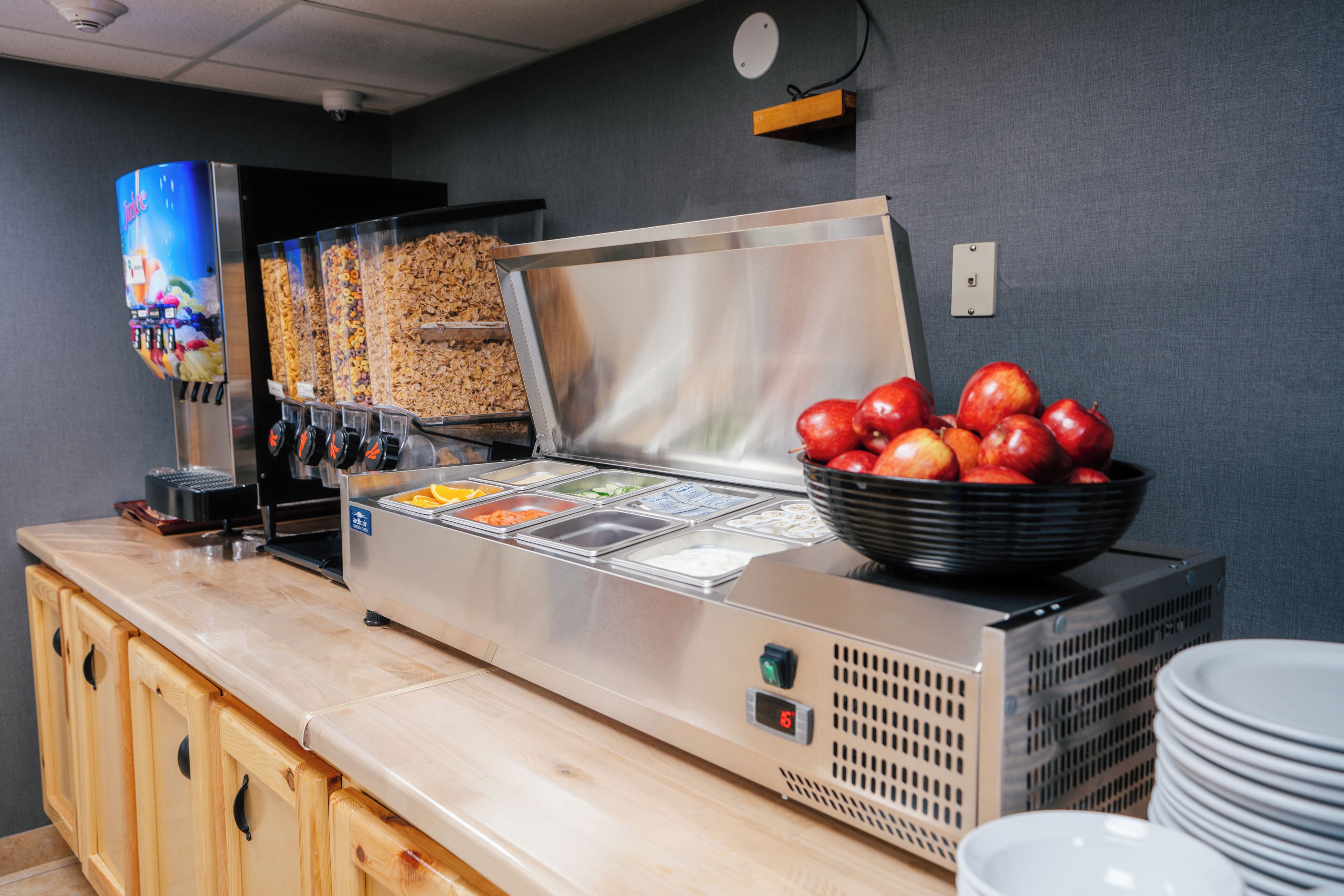 Disposição de buffet com diversos alimentos e uma tigela de maçãs em um balcão.