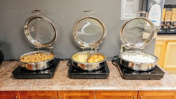 Een buffetopstelling met drie voedseldispensers op een aanrecht.