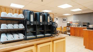 A coffee station with multiple coffee makers and a display of white cups.