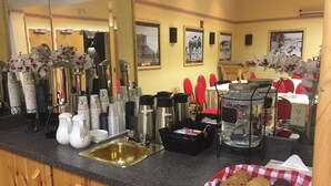 A breakfast bar with coffee makers, tea kettles, and a fruit basket. - Brewster Mountain Lodge (Banff)