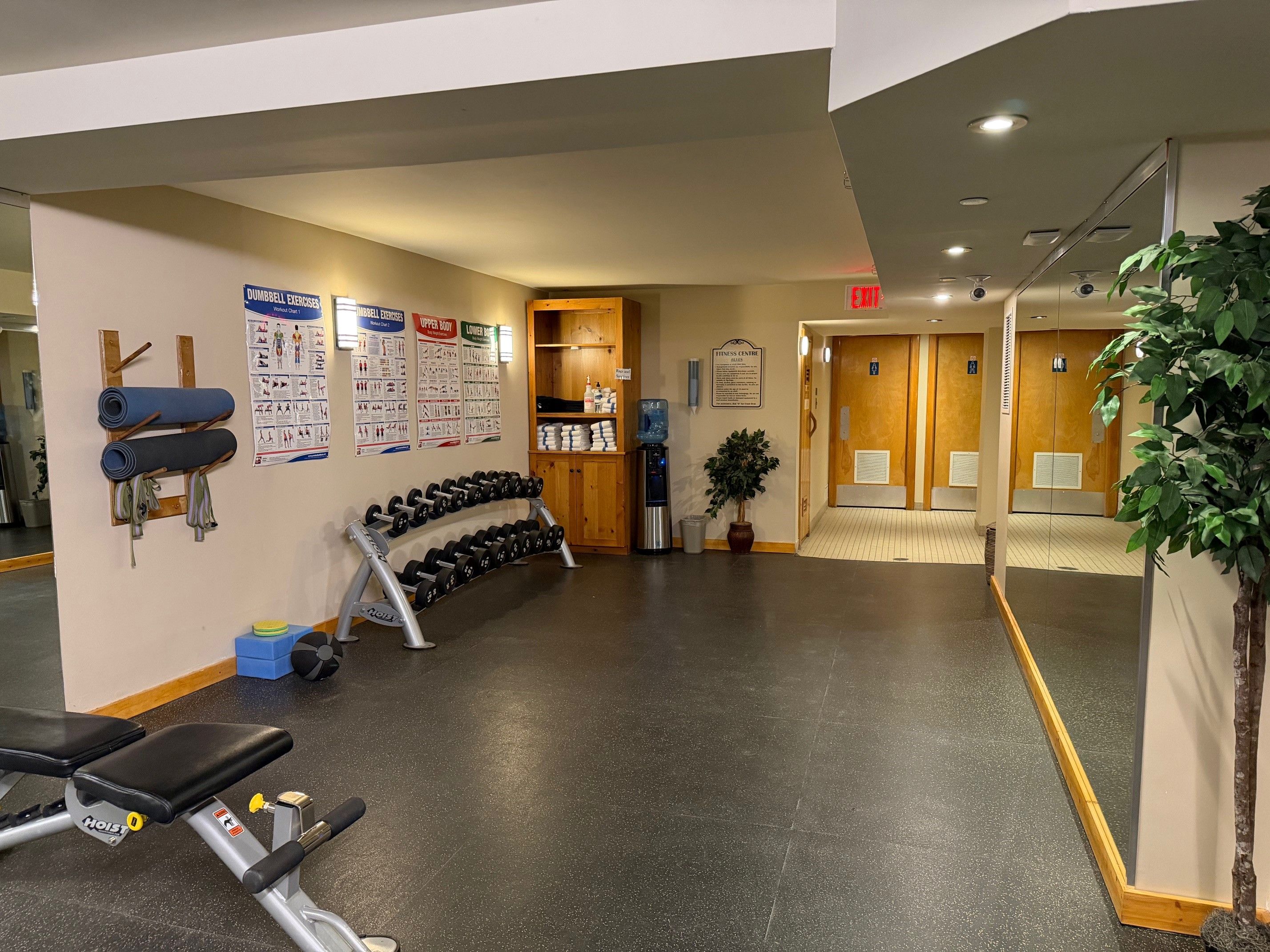 A gym with exercise equipment, informational posters, and a water dispenser.