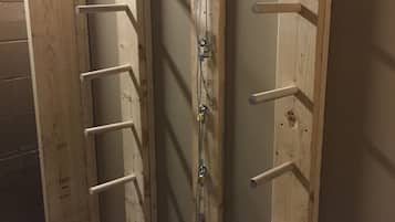 Esquina de una habitación con paredes de madera y un sistema de estanterías metálicas para colgar objetos.
