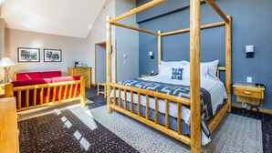 A room with a four-poster bed, a red sofa, a desk, and a lamp. - Brewster Mountain Lodge (Banff)