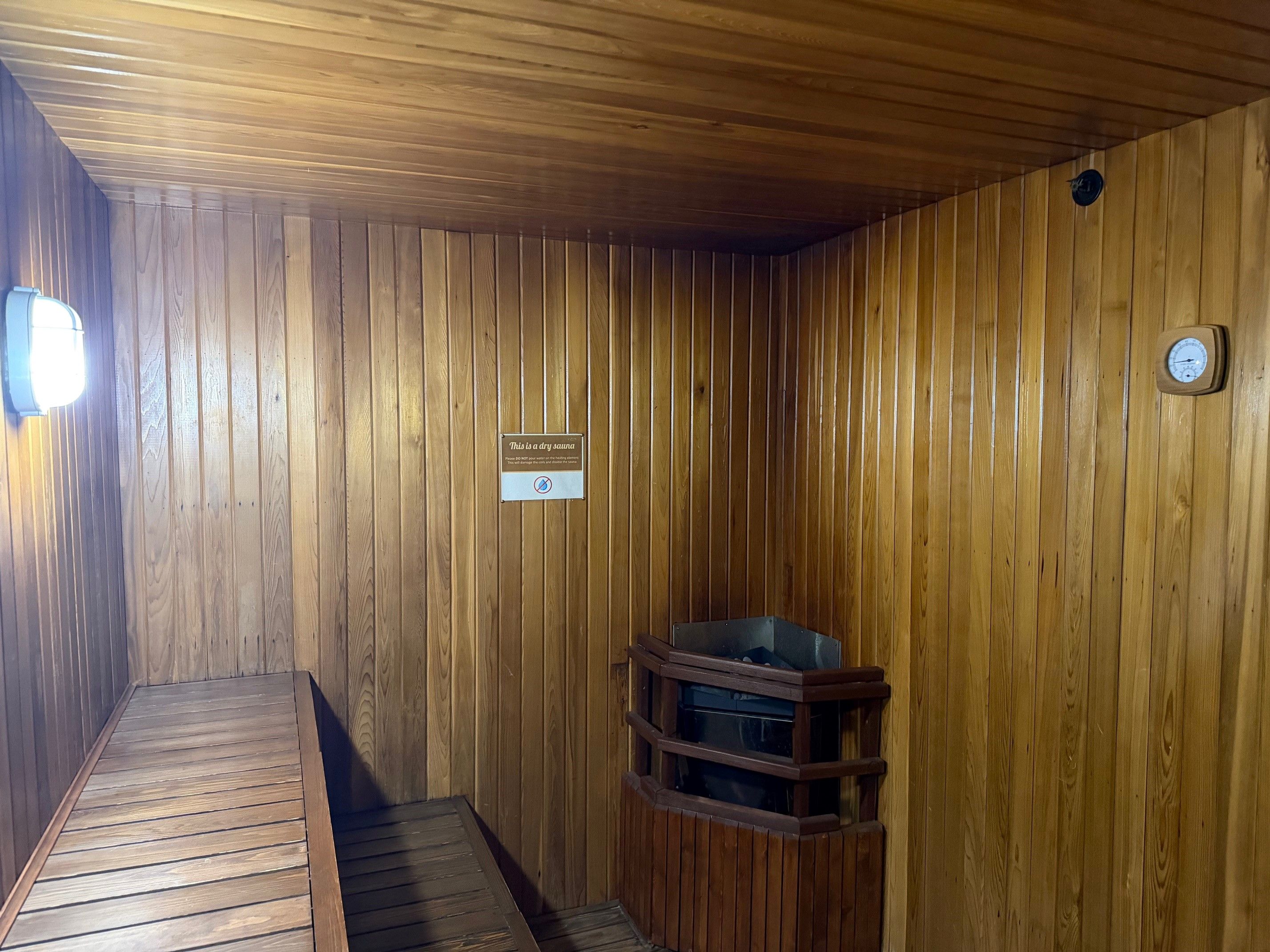 Una sauna seca con paredes de madera, un banco y un indicador de temperatura.