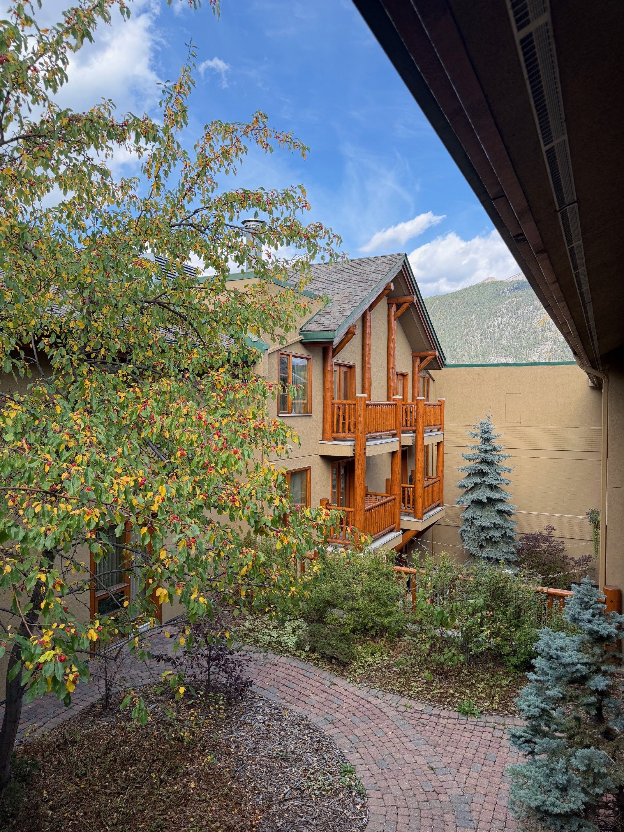 A two-story building with a balcony, surrounded by trees and a mountain view.