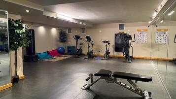 A gym with exercise equipment, a bench, and a mirrored wall.