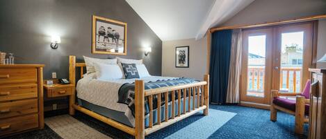 A bedroom with a wooden bed, a dresser, a desk, and a balcony with a chair.