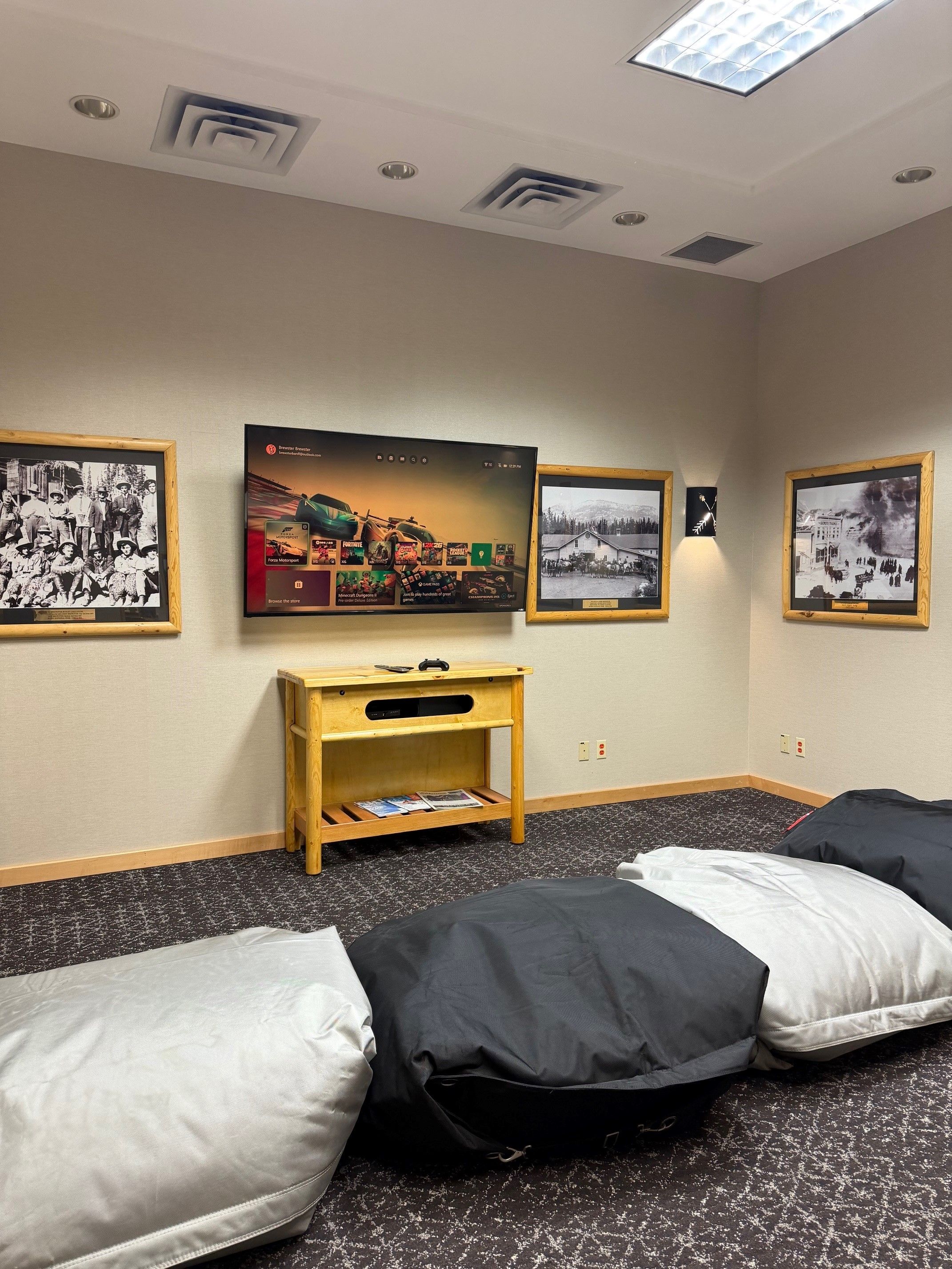 A hotel room with a television, framed pictures on the wall, a small wooden table, and two beds with pillows.