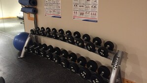 A gym with a wall-mounted dumbbell rack and exercise posters. - Brewster Mountain Lodge (Banff)