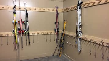 A ski storage room with multiple racks for skis and ski poles.