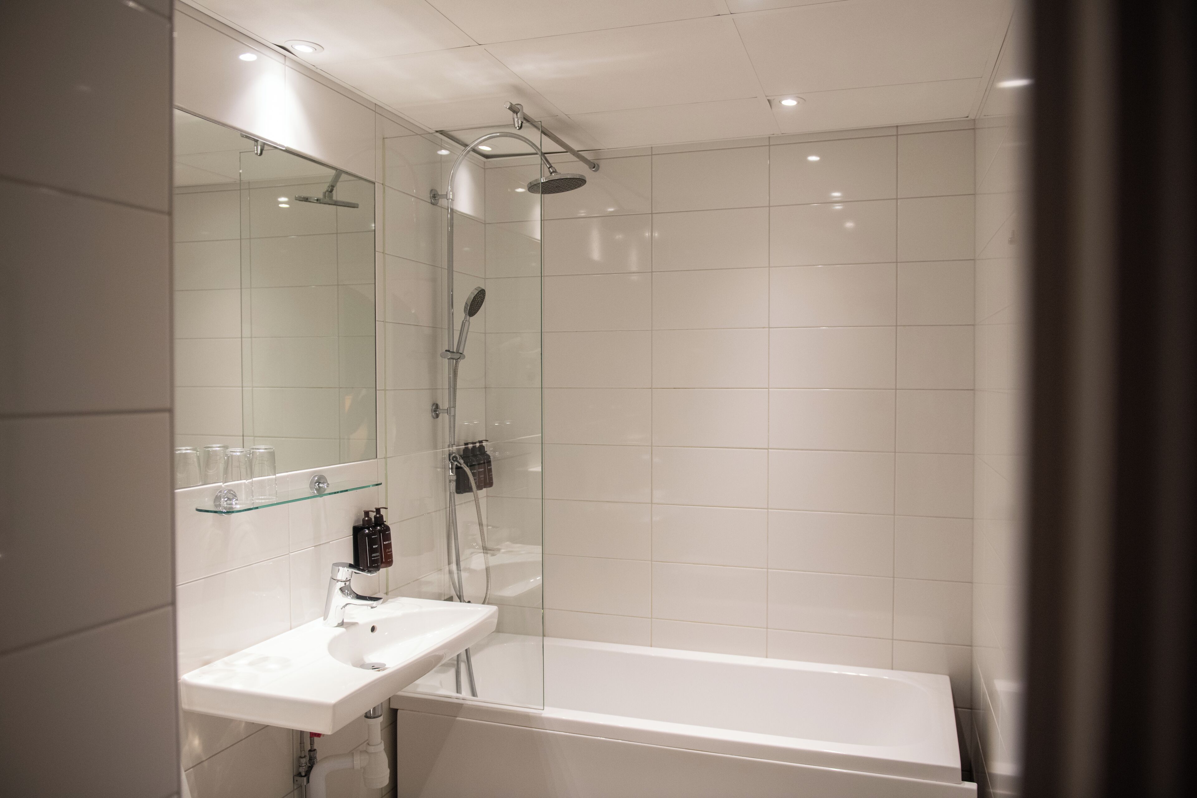 A modern bathroom with a glass-enclosed shower, a white sink, and a bathtub.