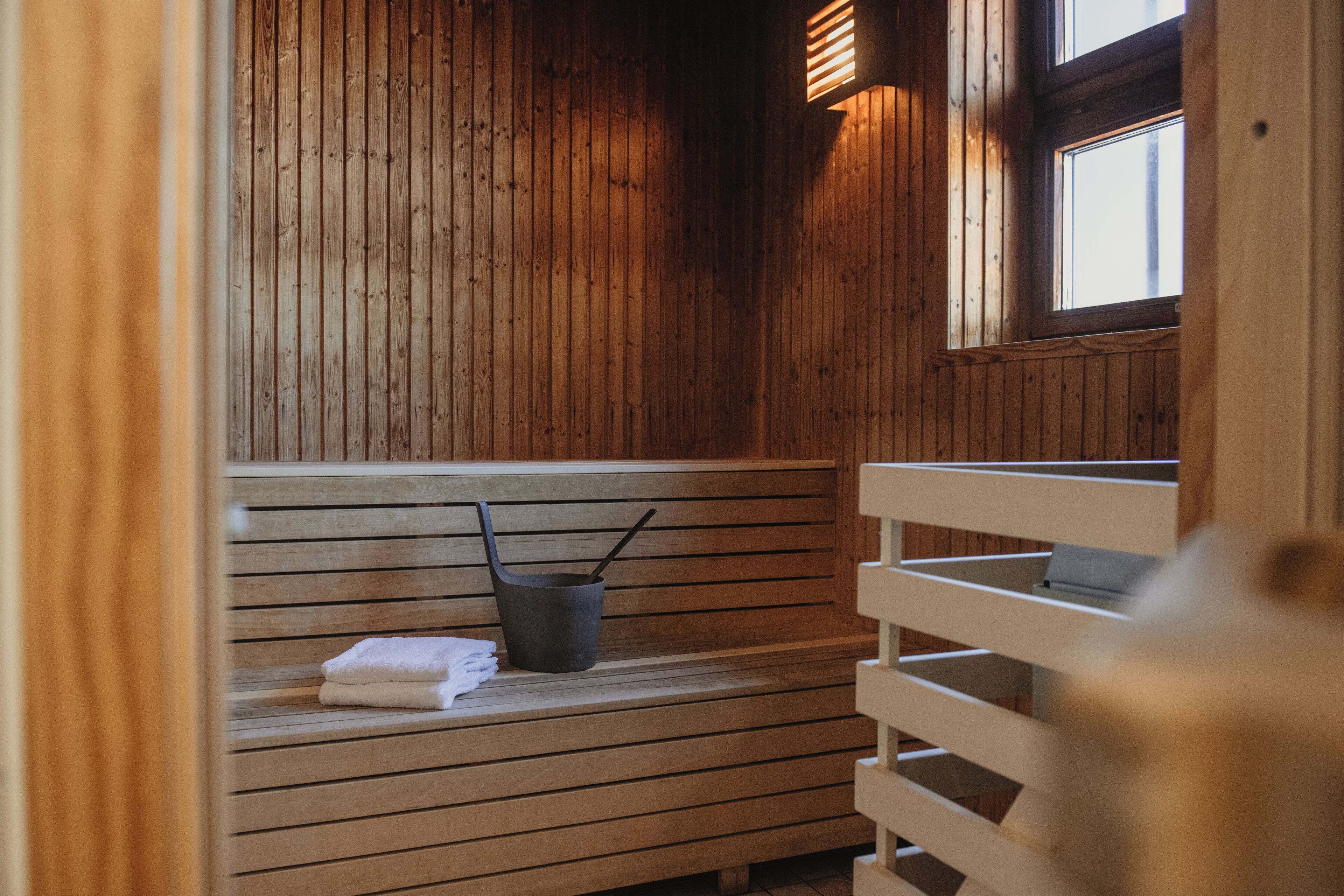 A wooden sauna with benches, a bucket, and towels.