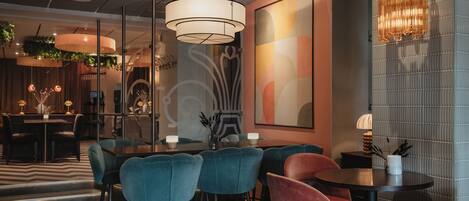 A modern dining area with a round table, blue and red chairs, and a decorative wall with abstract art.
