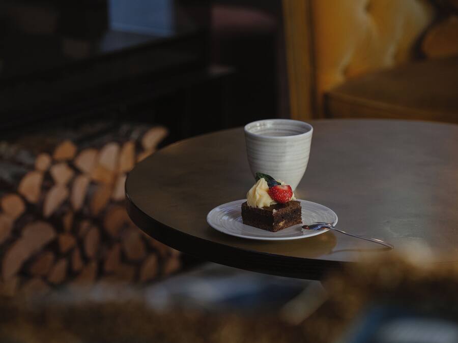 A dessert on a white plate with a spoon on a round table.