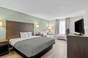 A hotel room with a bed, a desk, a chair, a TV, and a window with curtains. - Quality Inn Ghent (Ghent)