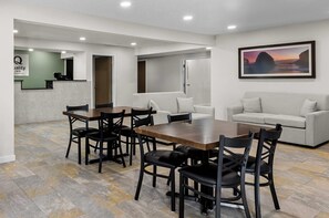 A hotel room with a dining area, a reception desk, and a painting on the wall. - Quality Inn Ghent (Ghent)