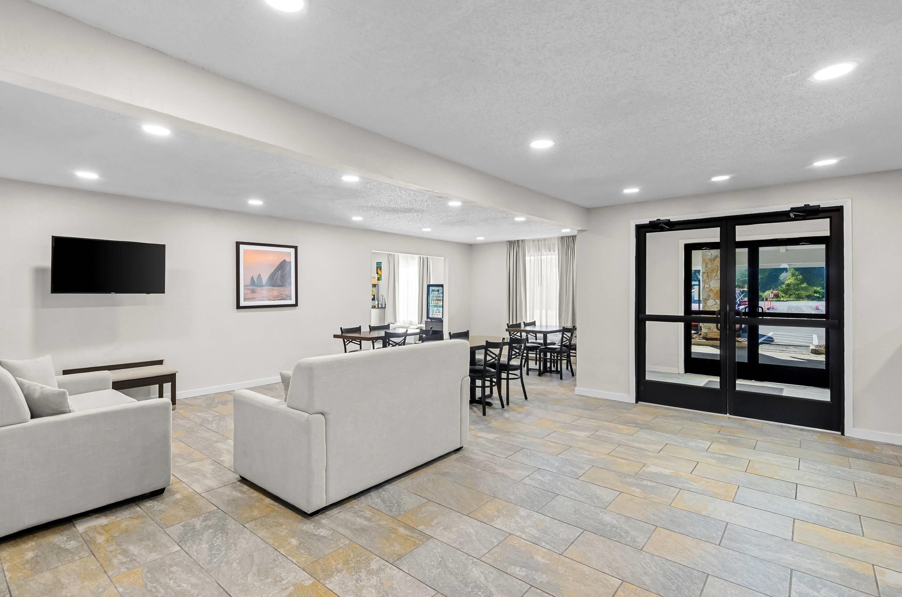 A spacious living area with a flat-screen TV, a sofa, and a dining table with chairs.
