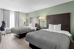 A hotel room with two beds, a desk, a chair, and a lamp. - Quality Inn Ghent (Ghent)