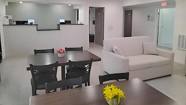 A modern interior with a dining area, a sofa, and a reception desk.