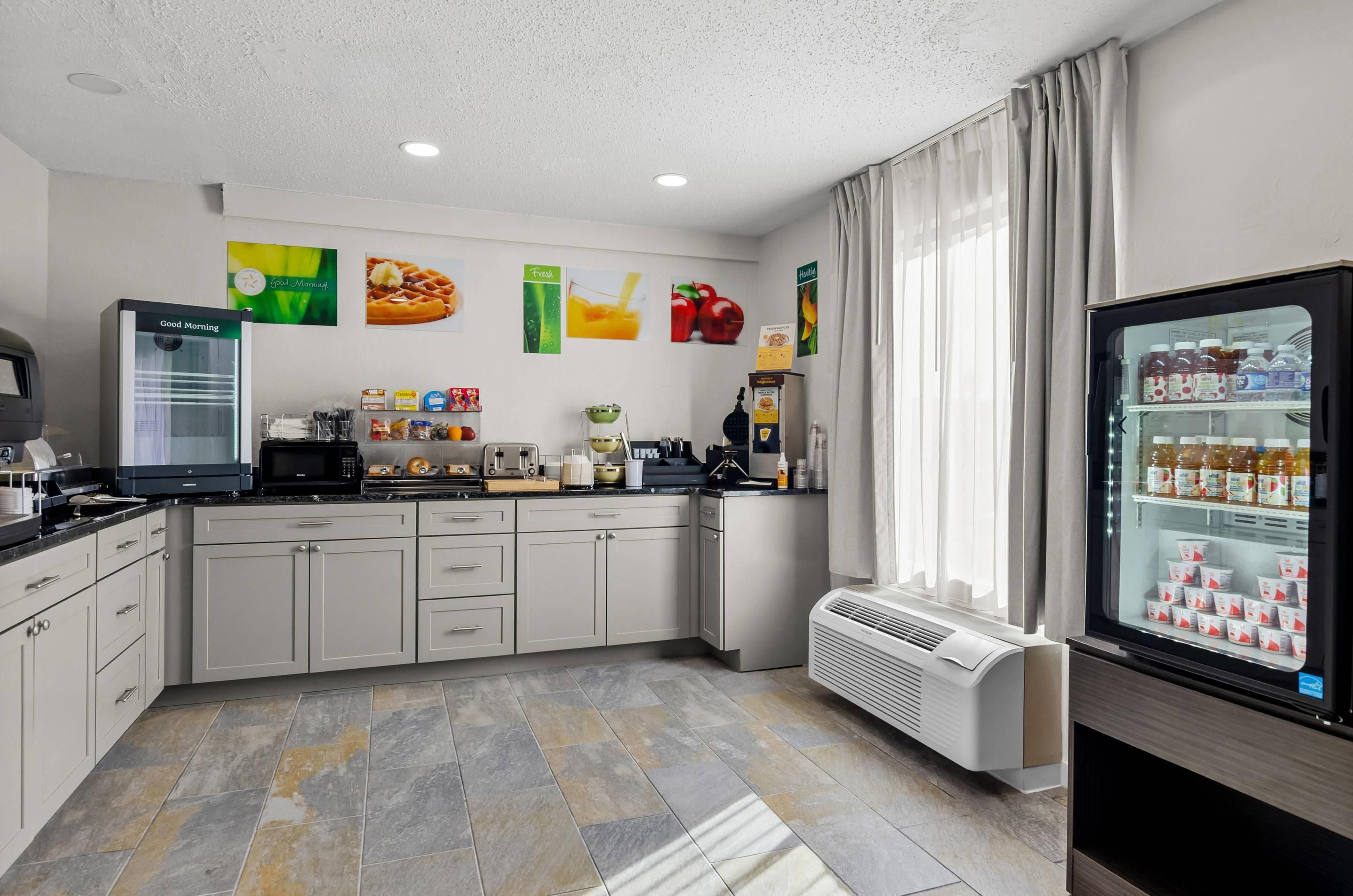 A modern kitchen with a refrigerator, microwave, and coffee maker.