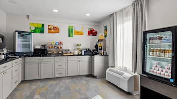 A modern kitchen with a refrigerator, microwave, and coffee maker.