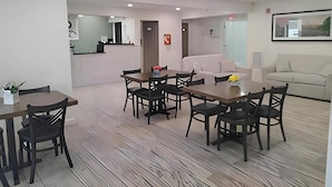 A modern interior with a dining area, a sofa, and a kitchen in the background.
