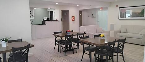 A modern interior with a dining area, a sofa, and a kitchen in the background.