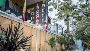 A hotel entrance with a stone wall, flags, and a balcony.