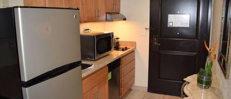 A compact kitchen with a refrigerator, microwave, and stove.