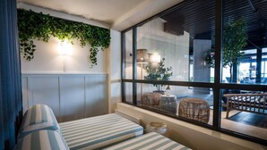 A room with two striped sofas, a window with a view of an outdoor seating area, and a wall decorated with green foliage. - Quality Hotel Tonsberg (Tønsberg)