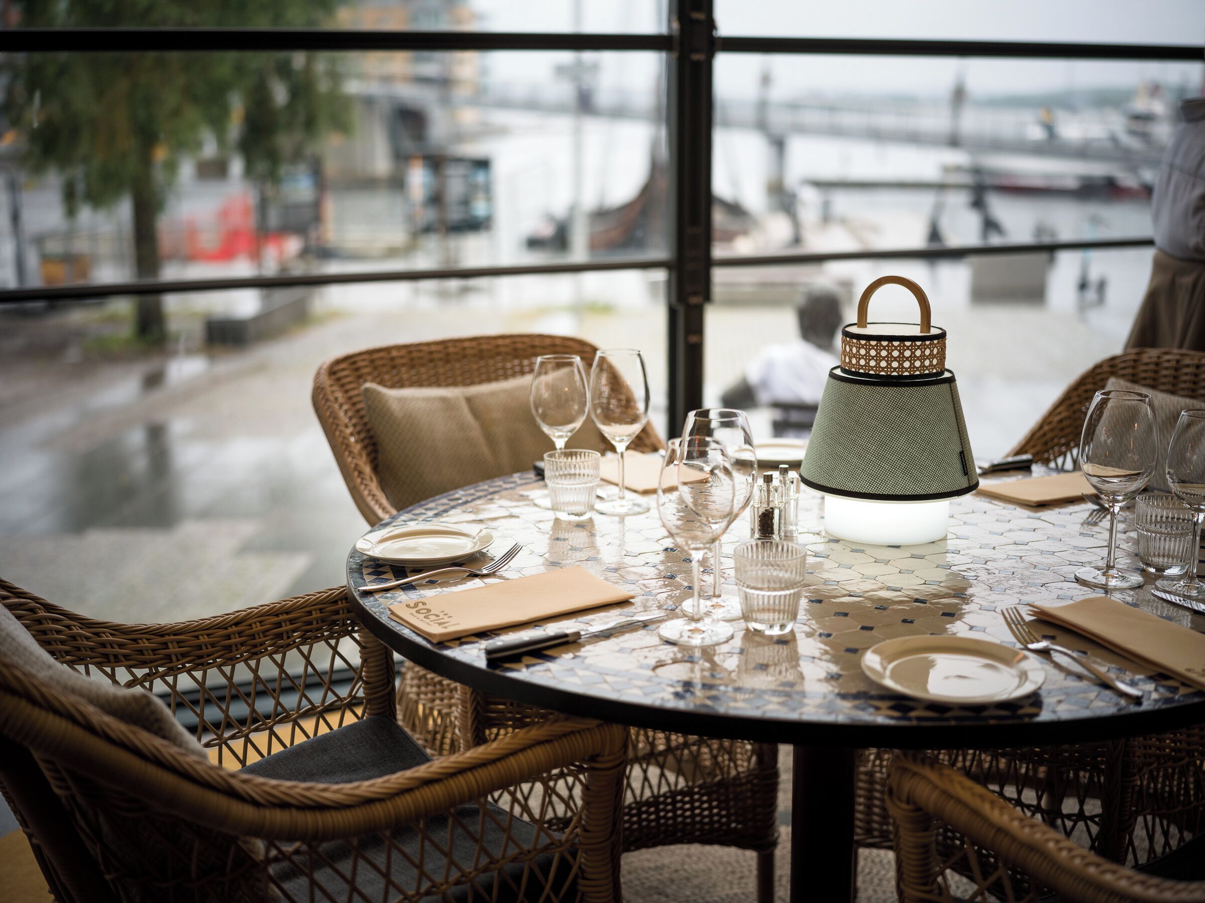 A round table with a mosaic top, surrounded by wicker chairs.