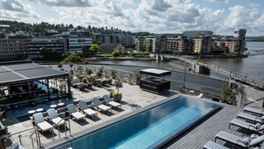 A rooftop swimming pool with lounge chairs and a bar area, overlooking a waterfront with buildings in the background. - Quality Hotel Tonsberg (Tønsberg)