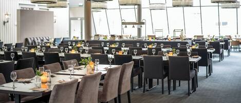 A spacious dining area with multiple tables, chairs, and elegant chandeliers.
