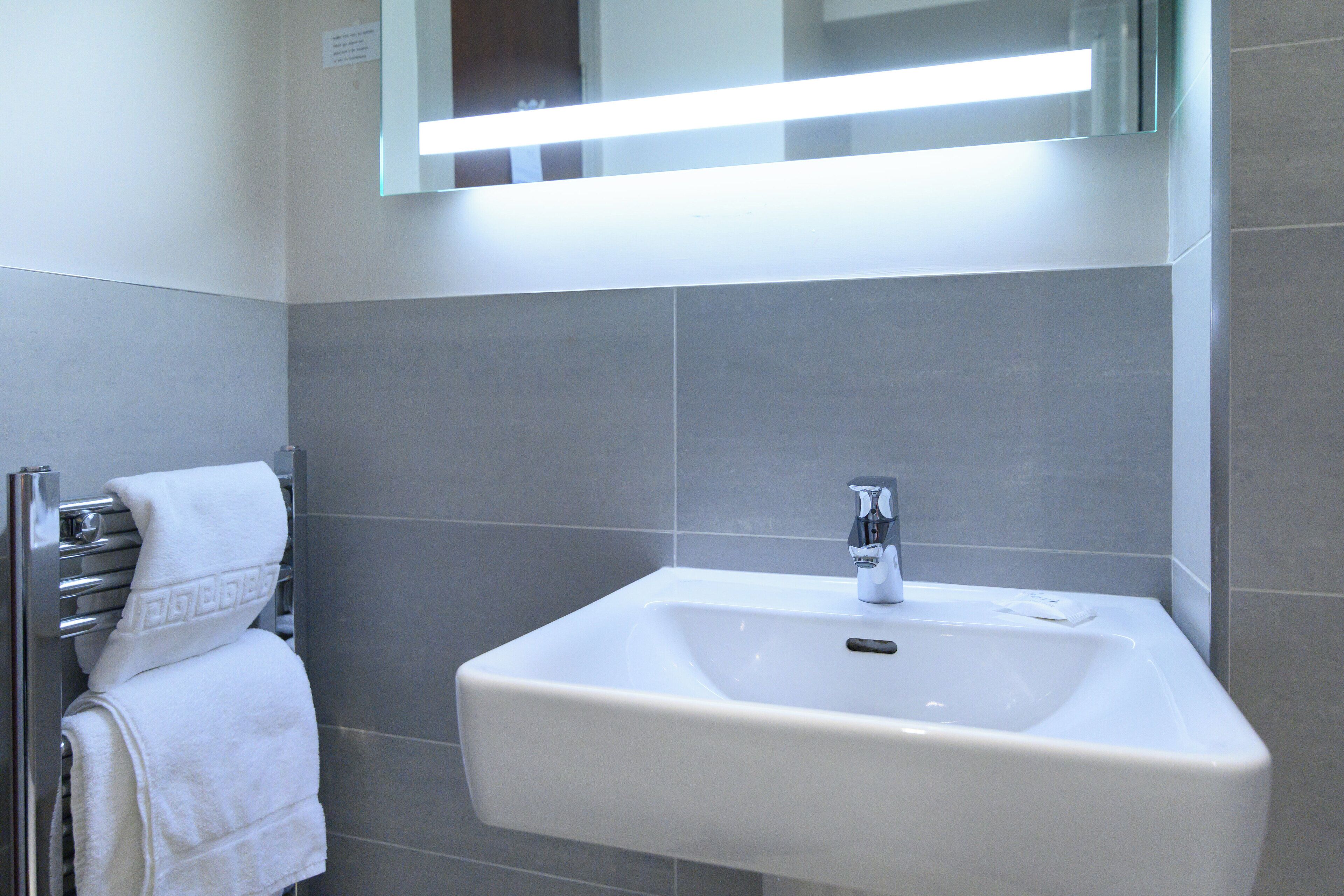 A bathroom with a white sink, chrome faucet, and towel rack.