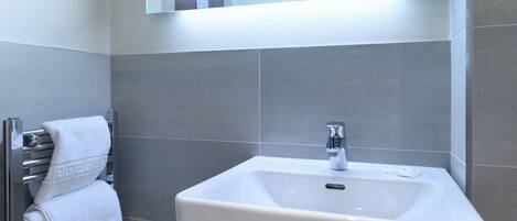 A bathroom with a white sink, chrome faucet, and towel rack.