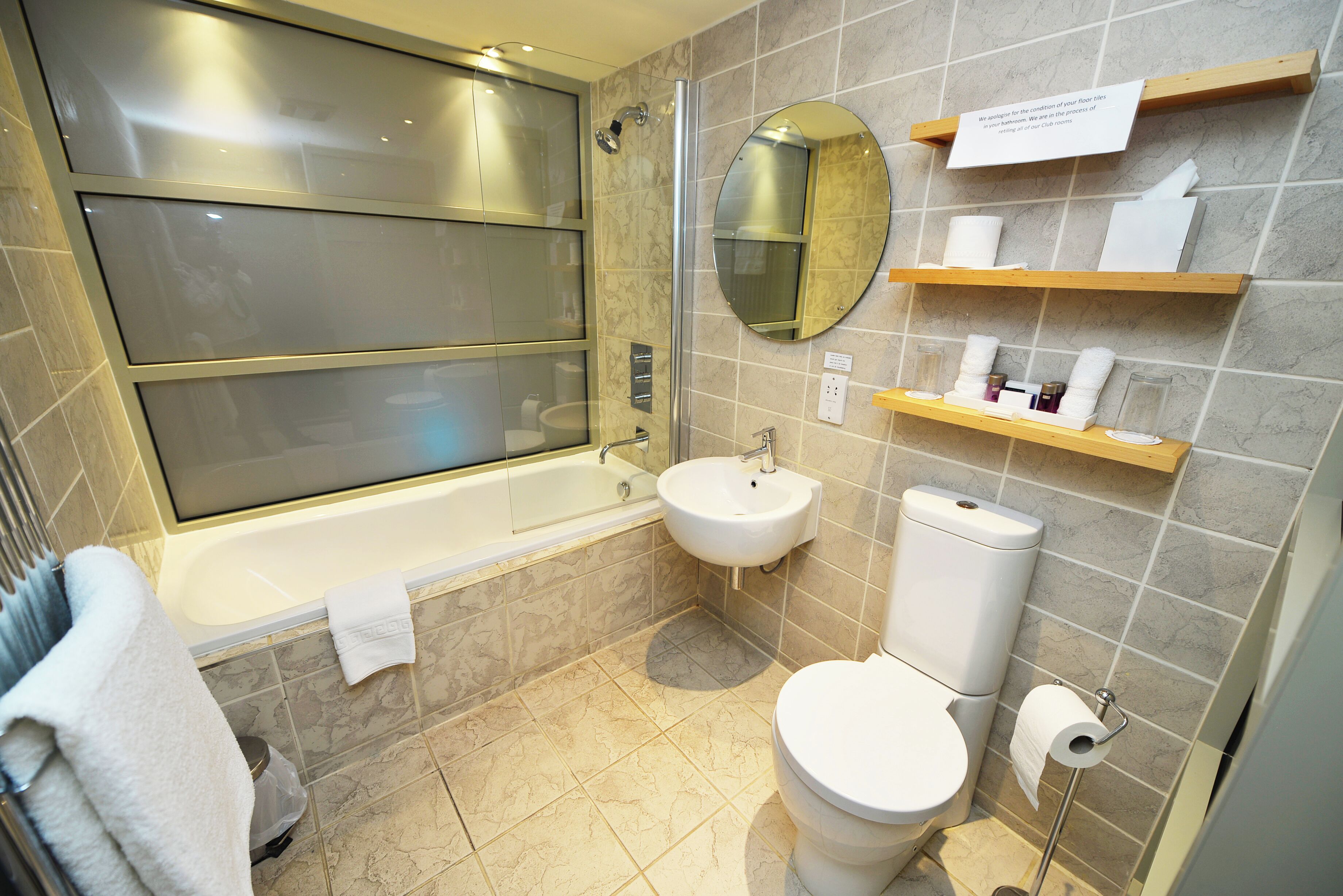 A modern bathroom with a bathtub, sink, toilet, and a mirror.