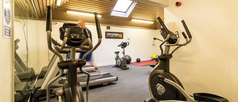 A gym with treadmills, elliptical machines, and exercise balls.