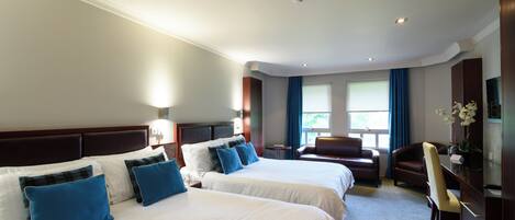 A hotel room with two beds, a desk, a chair, and a television.