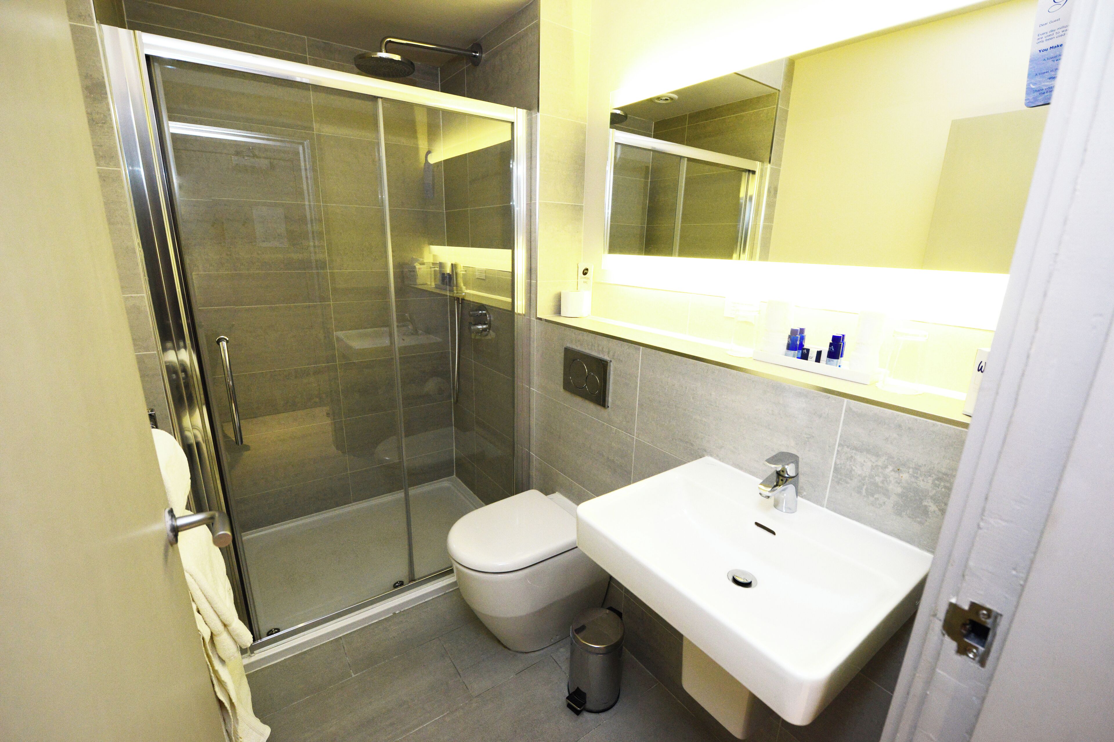 A modern bathroom with a glass-enclosed shower, a white sink, and a toilet.