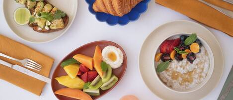 Desayuno con cruasanes, fruta y un tazón de avena.