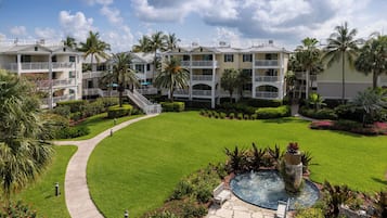 Surrounded by lush greenery and palm trees, this resort offers a serene escape with a central fountain and scenic views from its multi-story buildings.