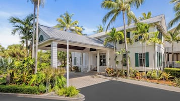 Un hôtel doté d’une entrée abritée, de palmiers et d’une allée pavée.