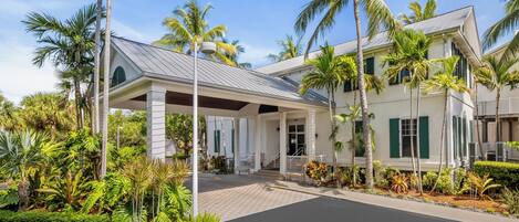 A hotel with a covered entrance, palm trees, and a paved driveway.