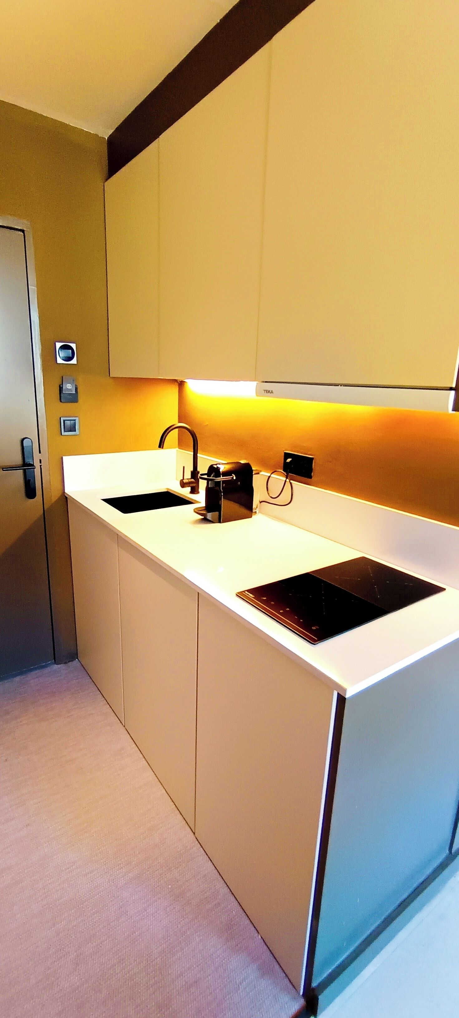 A modern kitchen with a white countertop, two sinks, and a built-in stove.