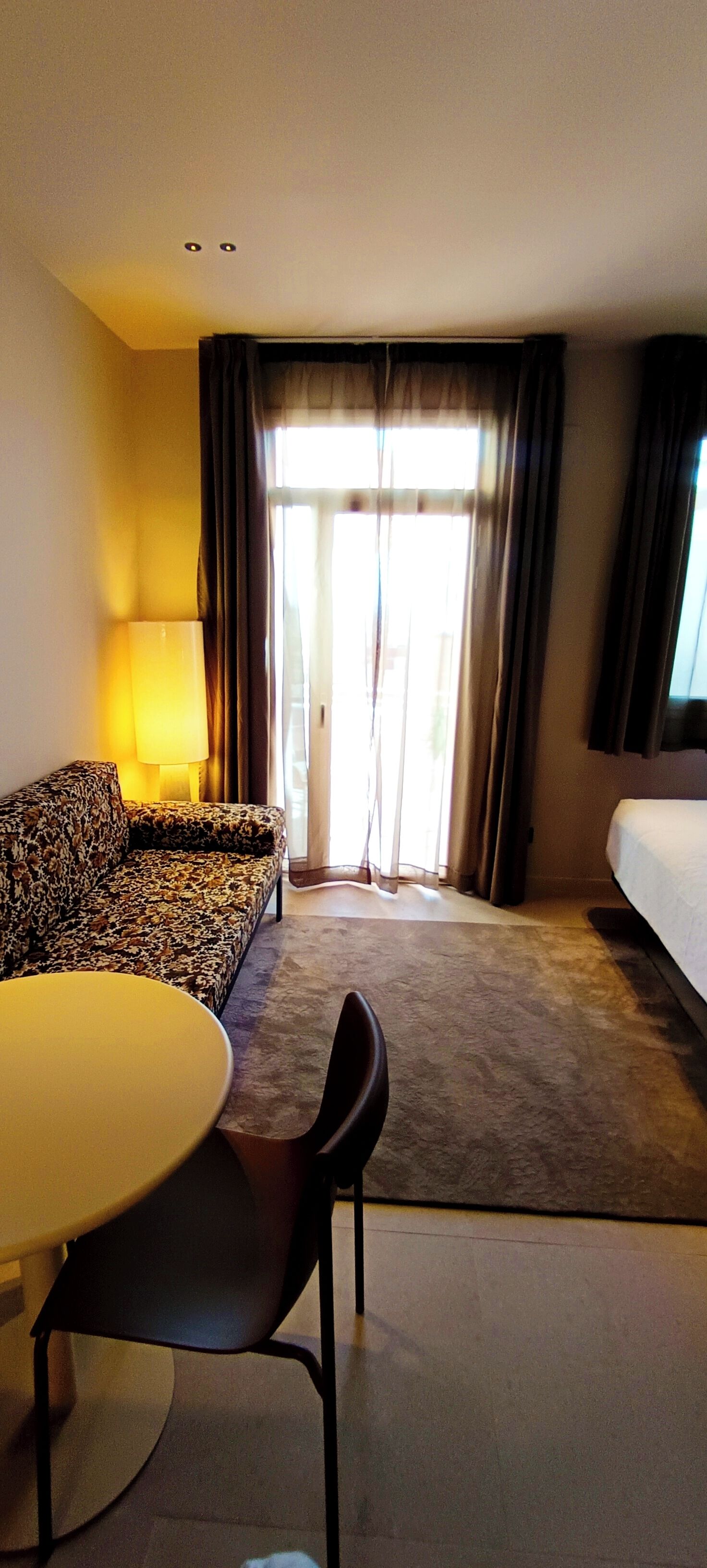 Una habitación de hotel con sofá, cama, mesa de comedor y una silla.